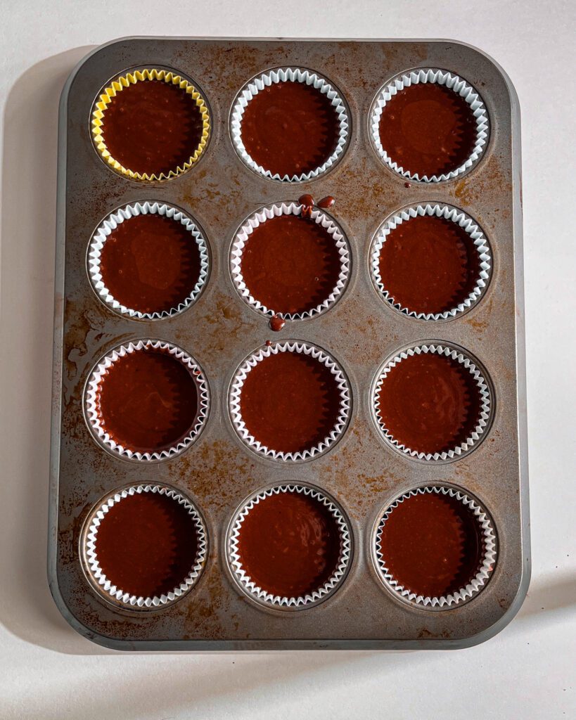 Cupcake liners filled with chocolate batter ready to bake