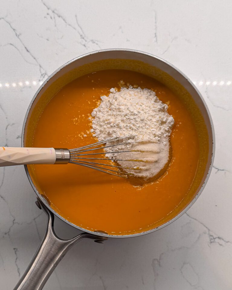 Adding sugar to Homemade mango curd cooking in saucepan