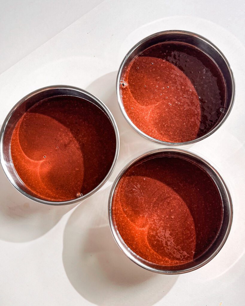 Chocolate cake batter in pans lined with parchment paper