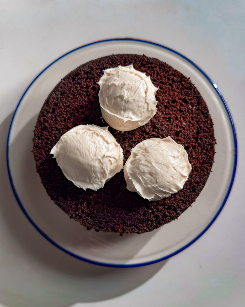 Cream cheese frosting spread between chocolate cake layers