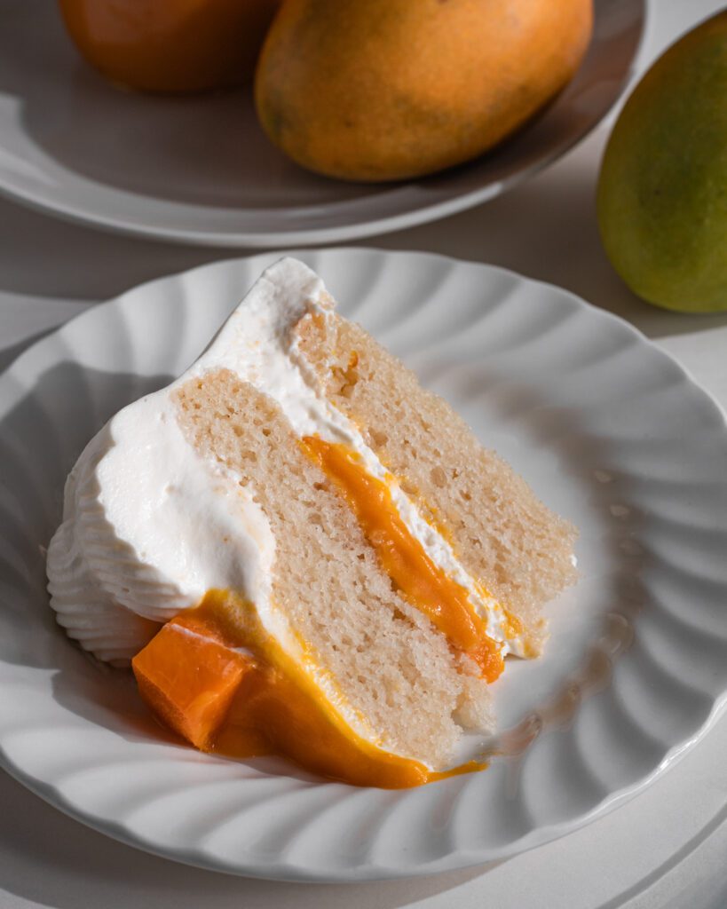 Slice of eggless and vegan soft mango cream cake on dessert plate