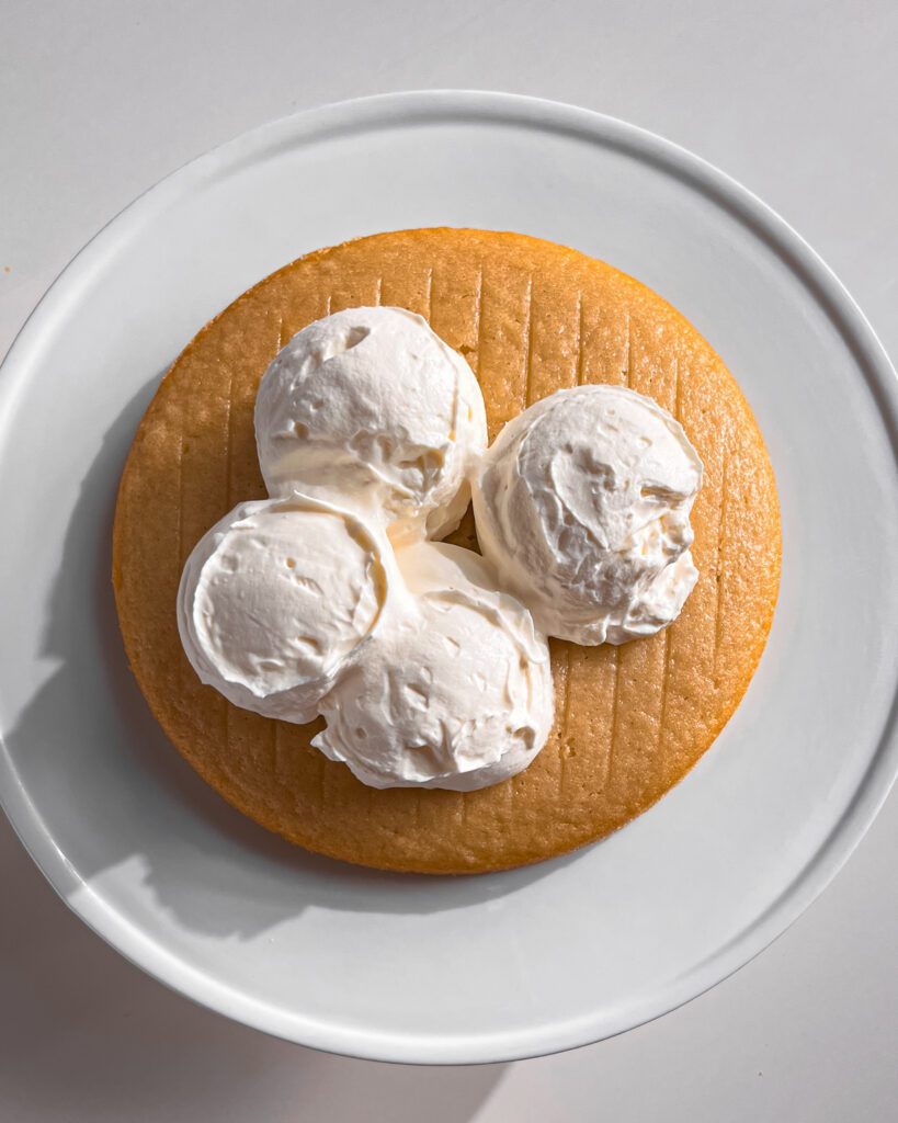 Whipped cream frosting being spread on cake layer