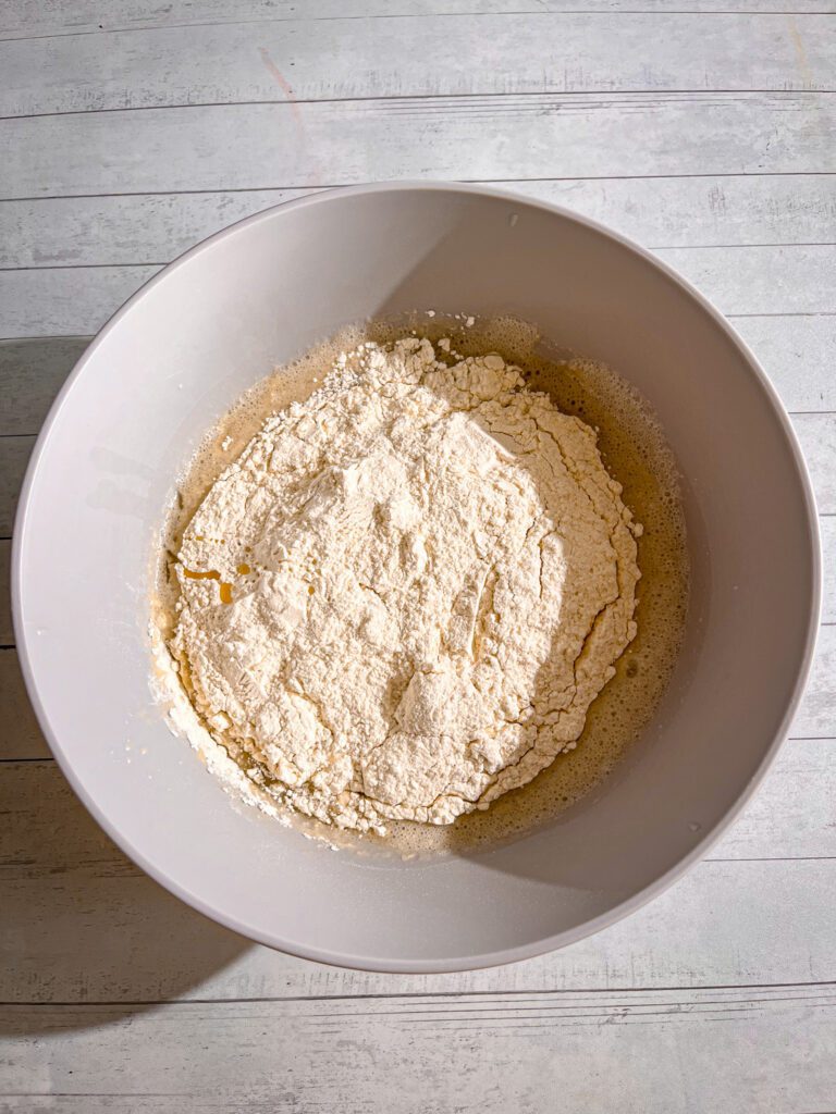 adding dry ingredients to eggless vanilla sponge cake batter and being mixed