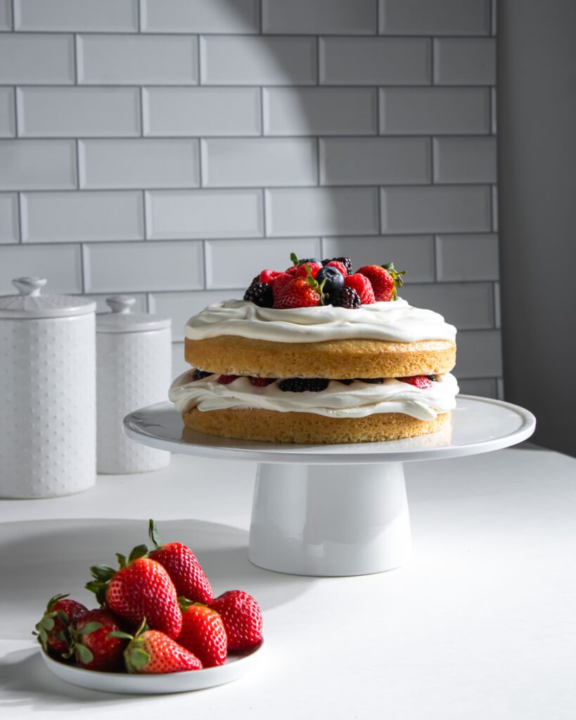Beautiful berries and cream cake decorated with seasonal fresh fruit.