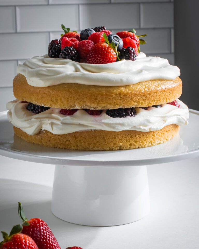 Eggless vanilla cake layer topped with whipped cream and fresh berries.