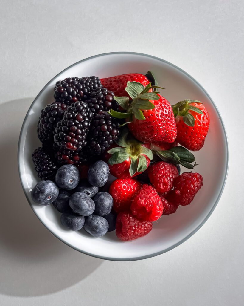 Fresh strawberries, blueberries, raspberries, and blackberries prepared for berry cake.