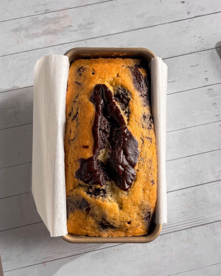 Freshly baked eggless marble loaf cake cooling in the pan