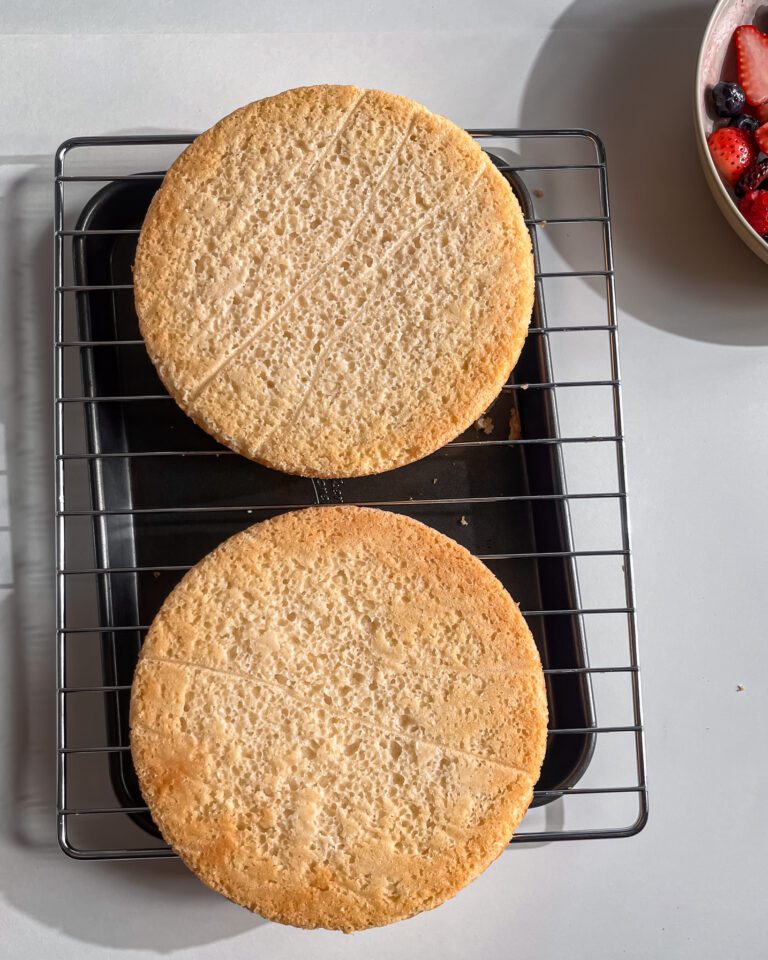 Freshly baked eggless vanilla sponge cakes cooling on a wire rack.