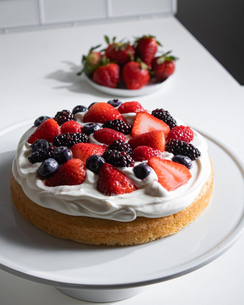 Layering fresh berries and whipped cream between cake layers.