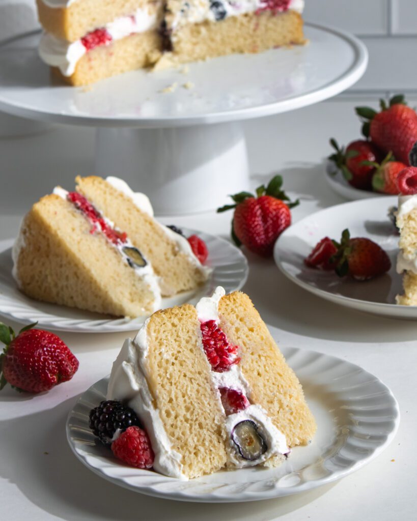 Slice of eggless berry cream cake filled with fresh berries and whipped cream.