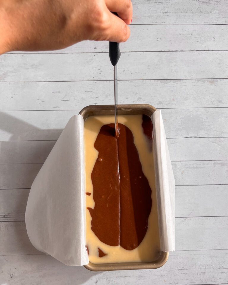 Swirling chocolate batter into vanilla batter using a skewer or knife
