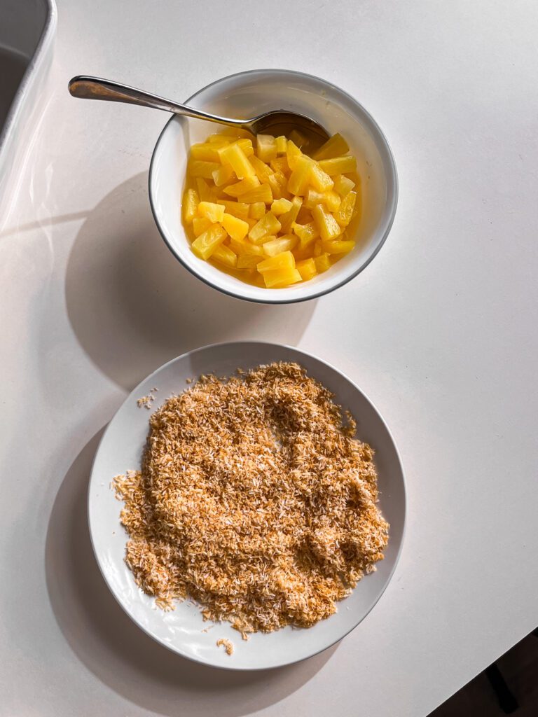 Adding crushed pineapple and shredded coconut to the pudding