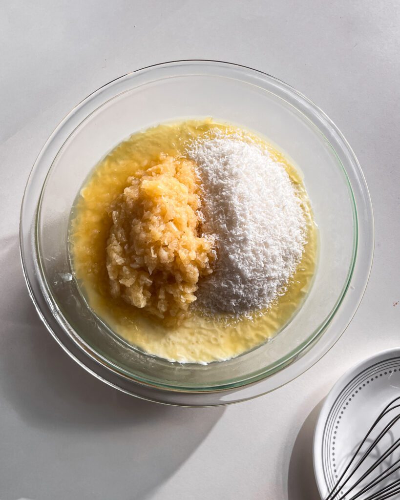 Adding crushed pineapple and shredded coconut to the pudding