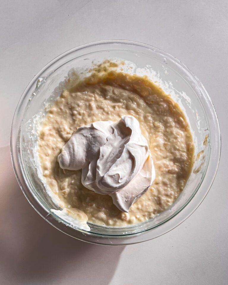 Folding whipped cream into chilled pineapple coconut pudding