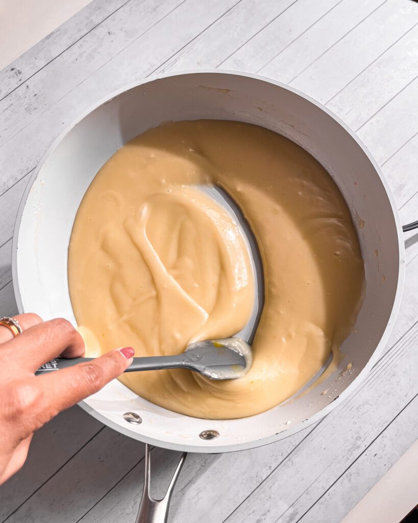 Homemade coconut custard cooking in a saucepan until thick and smooth.