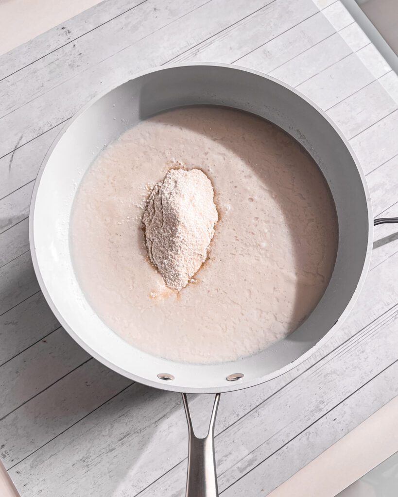 Stirring creamy coconut custard while it thickens over medium heat.