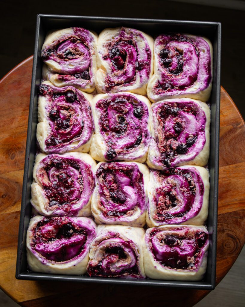 Arranging blueberry cinnamon rolls in a baking pan
