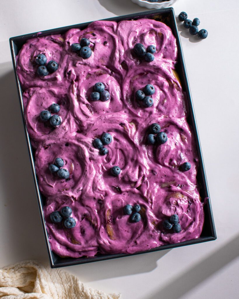Freshly baked eggless and vegan blueberry cinnamon rolls with blueberry frosting