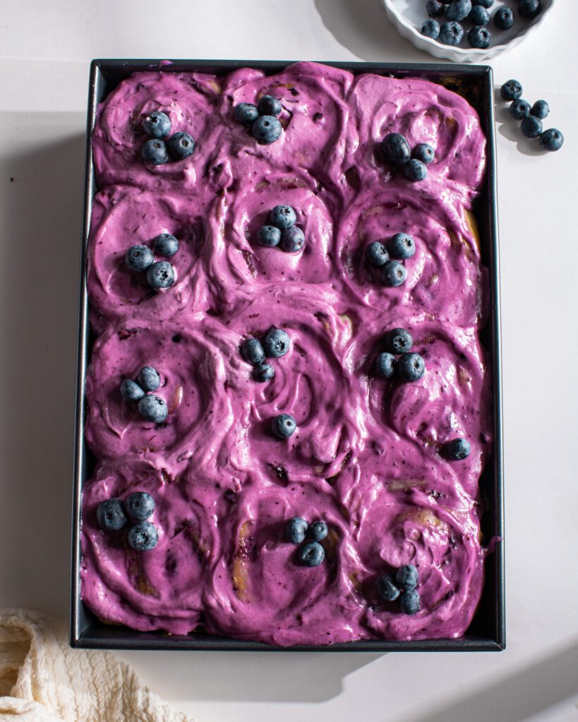 Freshly baked vegan blueberry cinnamon rolls with blueberry frosting