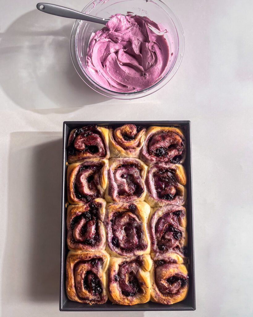 Ready for Spreading blueberry frosting over warm cinnamon rolls