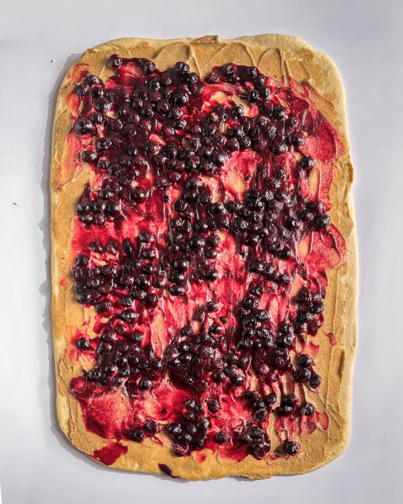 Spreading blueberry jam over cinnamon sugar filling