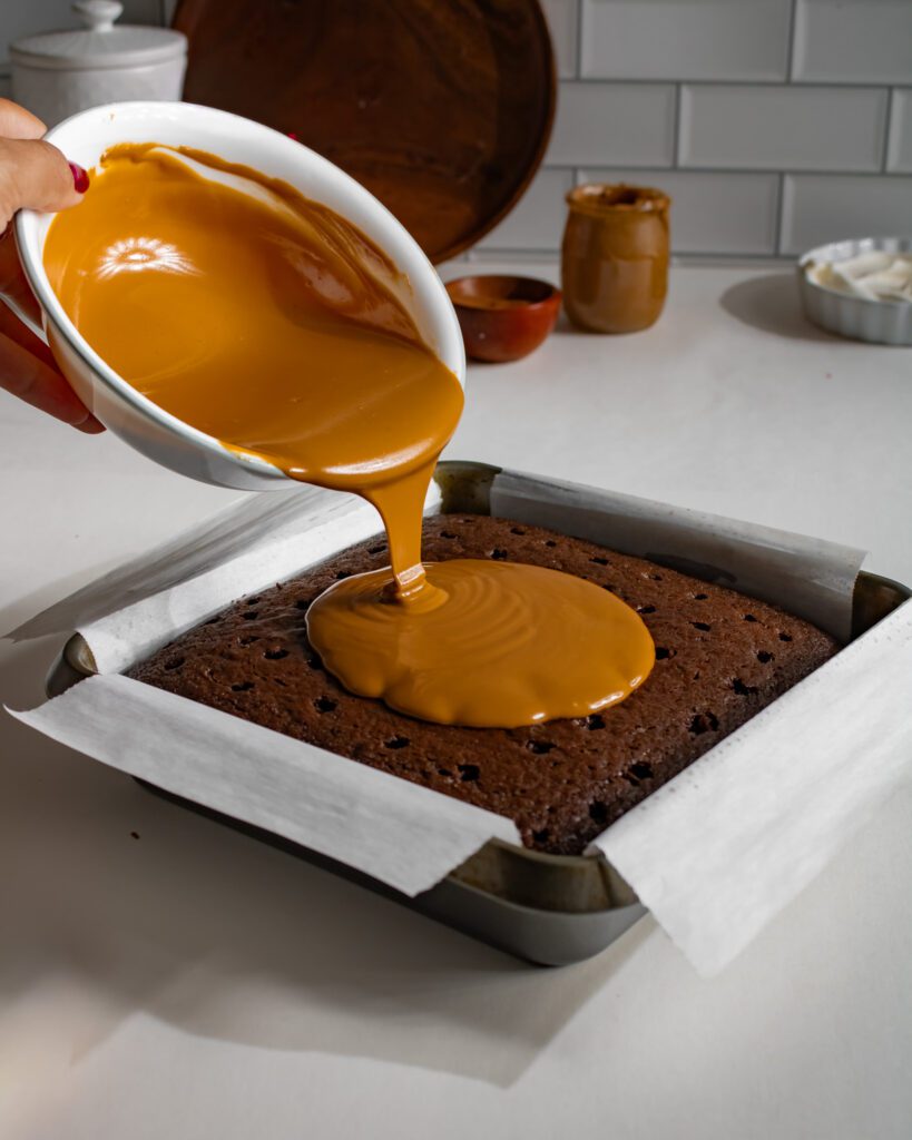 Melted Biscoff spread poured over a chocolate cake with holes