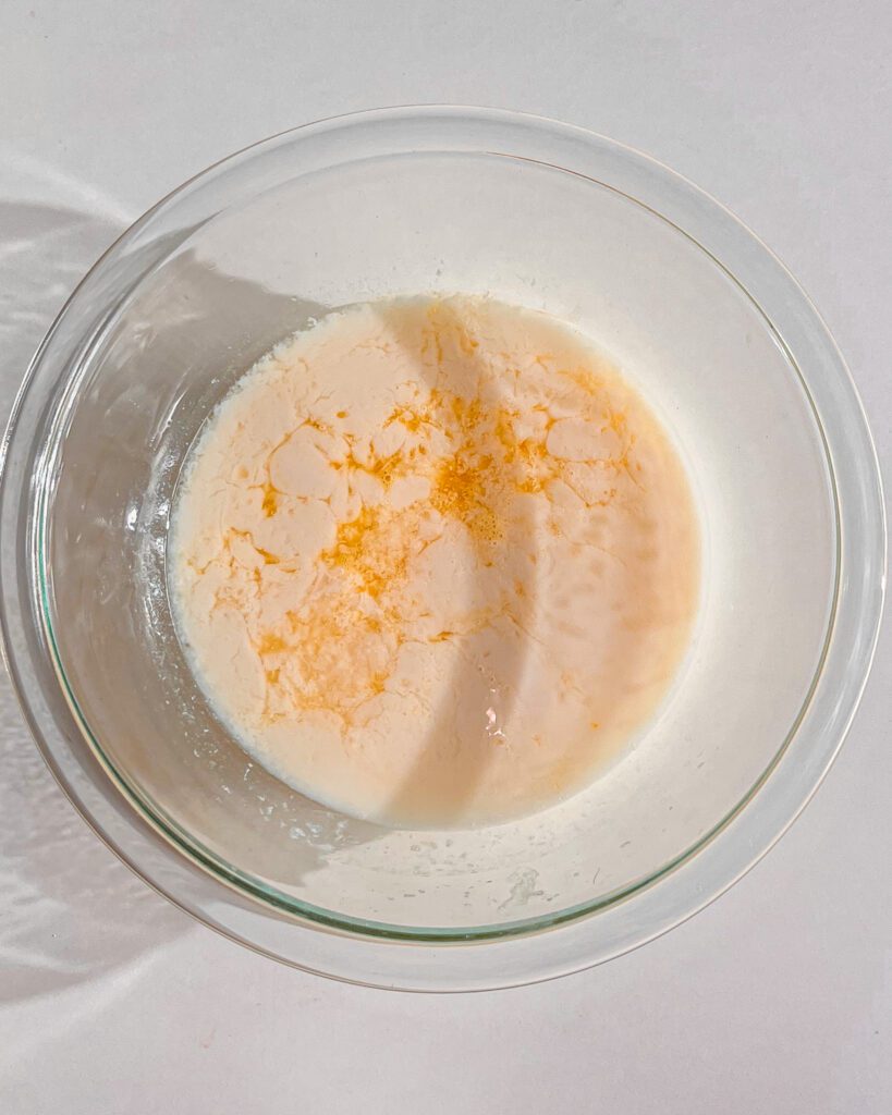 Orange juice, milk, oil, vanilla, and orange-infused sugar mixed for eggless loaf cake
