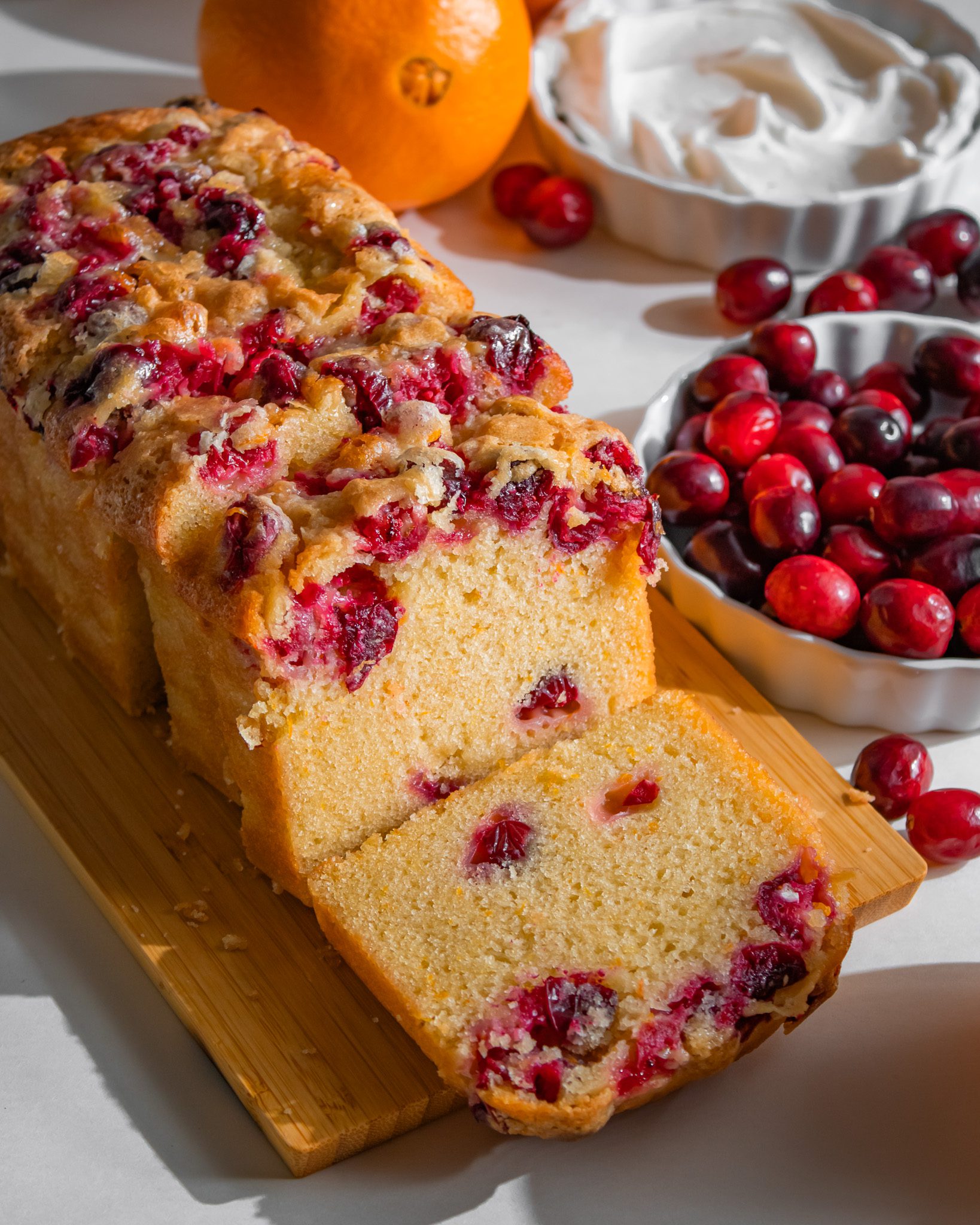 Eggless orange cranberry loaf cake topped with sugar and filled with tart cranberries